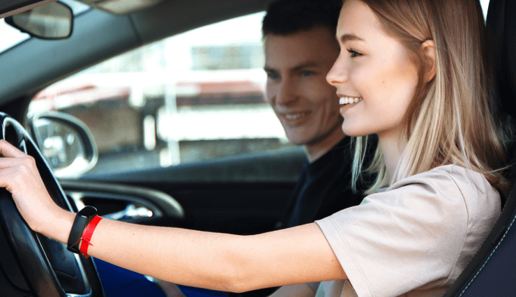 Young woman learning to drive with instructor.