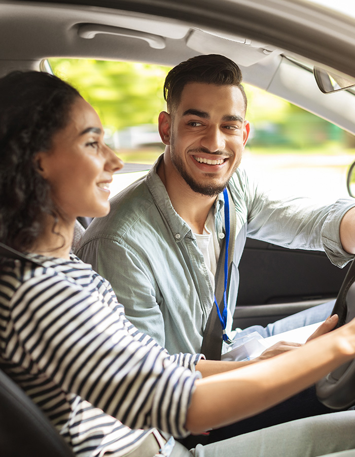 Driving instructor teaching student with a smile.